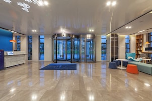 Un vestíbulo moderno con puerta giratoria, mostrador de recepción y zona de estar.