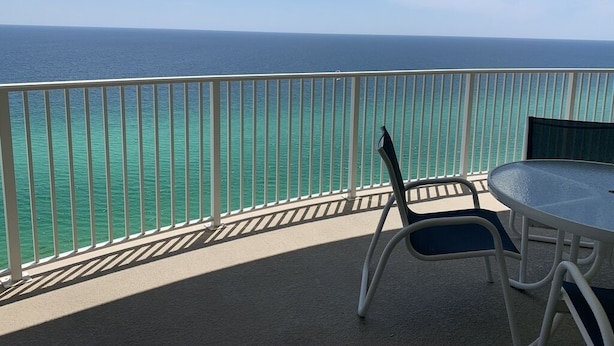 Een balkon met uitzicht op de oceaan, een ronde tafel en een stoel.