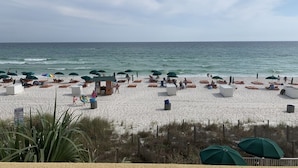 Een strand met wit zand, parasols en ligstoelen.