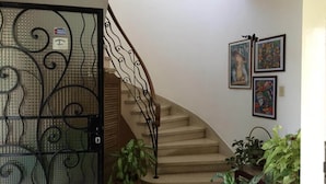 A staircase with a metal railing leading to a landing. There are potted plants on the landing and a door with a metal gate. - Casa Miramar Ileana Abella MIRAMAR (Havana)