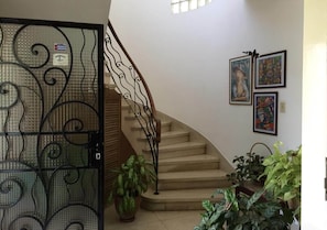 A staircase with a metal railing leading to a landing. There are potted plants on the landing and a door with a metal gate. - Casa Miramar Ileana Abella MIRAMAR (Havana)