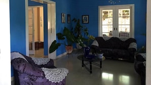 A living room with blue walls, two sofas, a coffee table, and large potted plants. - Casa Miramar Ileana Abella MIRAMAR (Havana)