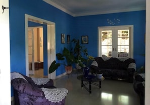 A living room with blue walls, two sofas, a coffee table, and large potted plants. - Casa Miramar Ileana Abella MIRAMAR (Havana)