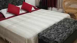 A bed with a patterned headboard, red and white pillows, and a matching footboard. - Casa Miramar Ileana Abella MIRAMAR (Havana)
