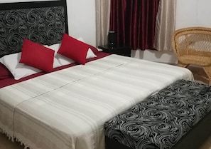A bed with a patterned headboard, red and white pillows, and a matching footboard. - Casa Miramar Ileana Abella MIRAMAR (Havana)