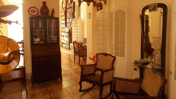 A traditional interior with a dining area, bookshelves, and a mirror. - Casa Novo Guest House CENTRO HABANA (Havana)
