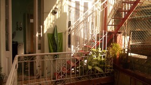 A balcony with wrought iron railings, a potted plant, and a view of a building with a window and a door. - Casa Novo Guest House CENTRO HABANA (Havana)
