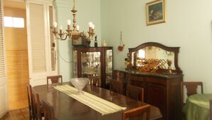 A dining room with a wooden table, chairs, a chandelier, a mirror, and a green tablecloth. - Casa Novo Guest House CENTRO HABANA (Havana)