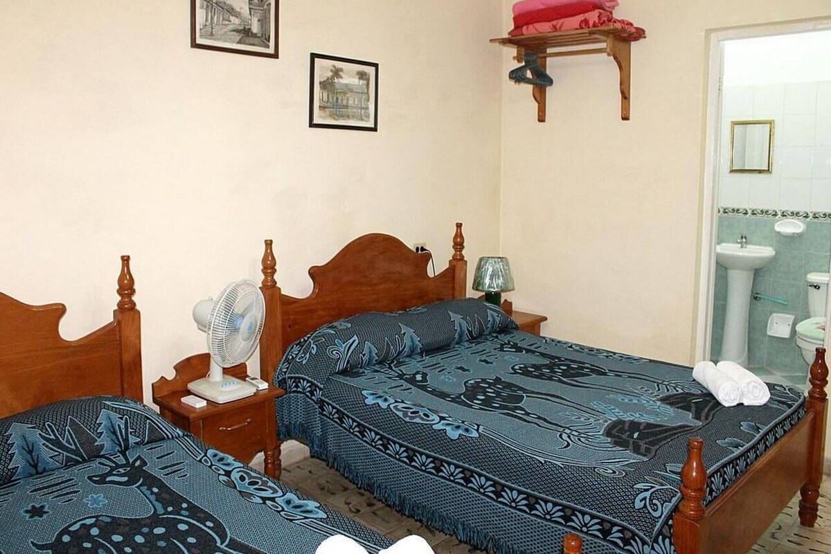 Ein Schlafzimmer mit zwei Holzbett, einem Nachttisch mit Lampe und einem an der Wand befestigten Regal mit einem rosafarbenen Gegenstand.
