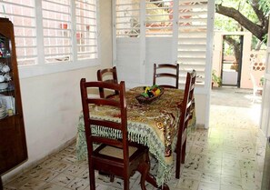 Uma sala de jantar com uma mesa posta para quatro pessoas, rodeada por cadeiras de madeira.