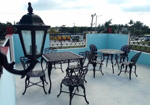 An outdoor patio with metal tables and chairs, a decorative lantern, and a blue wall in the background. - Hostal Betty SANTA MARTA (Cárdenas)