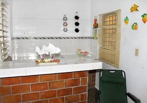 Kitchen area with a countertop, brick backsplash, and hanging items.
