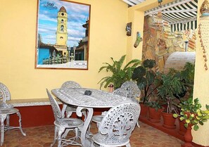 Relax and socialize in this inviting patio area, complete with a round table and matching chairs, surrounded by lush greenery and a cultural touch.