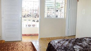 A bedroom with a bed, a door, and a window. - Hostal El Corojo TRINIDAD (Trinidad)