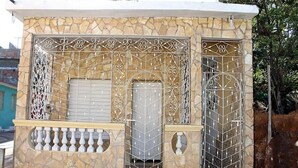 A stone building with a metal gate and a balcony. - Hostal El Corojo TRINIDAD (Trinidad)