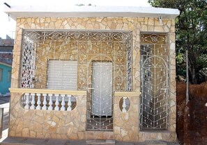 A stone building with a metal gate and a balcony. - Hostal El Corojo TRINIDAD (Trinidad)