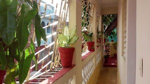 A corridor with potted plants on a balcony, a tiled floor, and a white railing. - Hostal El Corojo TRINIDAD (Trinidad)