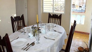 A dining table set for four with white tablecloth, plates, cutlery, and wine glasses. - Hostal El Corojo TRINIDAD (Trinidad)