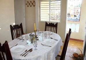 A dining table set for four with white tablecloth, plates, cutlery, and wine glasses. - Hostal El Corojo TRINIDAD (Trinidad)