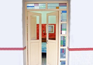 Enter a cozy space with a door leading to another area, featuring a red brick wall and a patterned floor.
