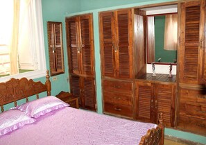 Ein Schlafzimmer mit einem Bett, einem Holzschrank und einem Spiegel.