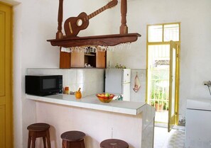 Eine kleine Küche mit einer Mikrowelle, einer Obstschale und einer an der Wand hängenden Gitarre.