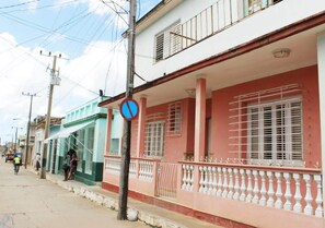 A street view with buildings, a no parking sign, and a person walking.
