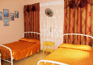 A room with two beds, a small table, and a fan.