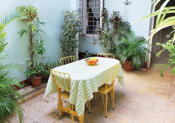 A small outdoor dining area with a table and chairs, surrounded by potted plants.