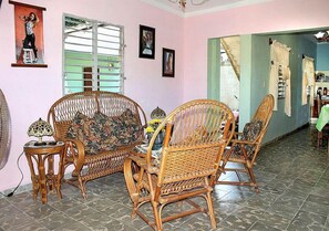 Relax in a traditional room with a rattan sofa and matching chairs, a small round table, and framed pictures on the wall.