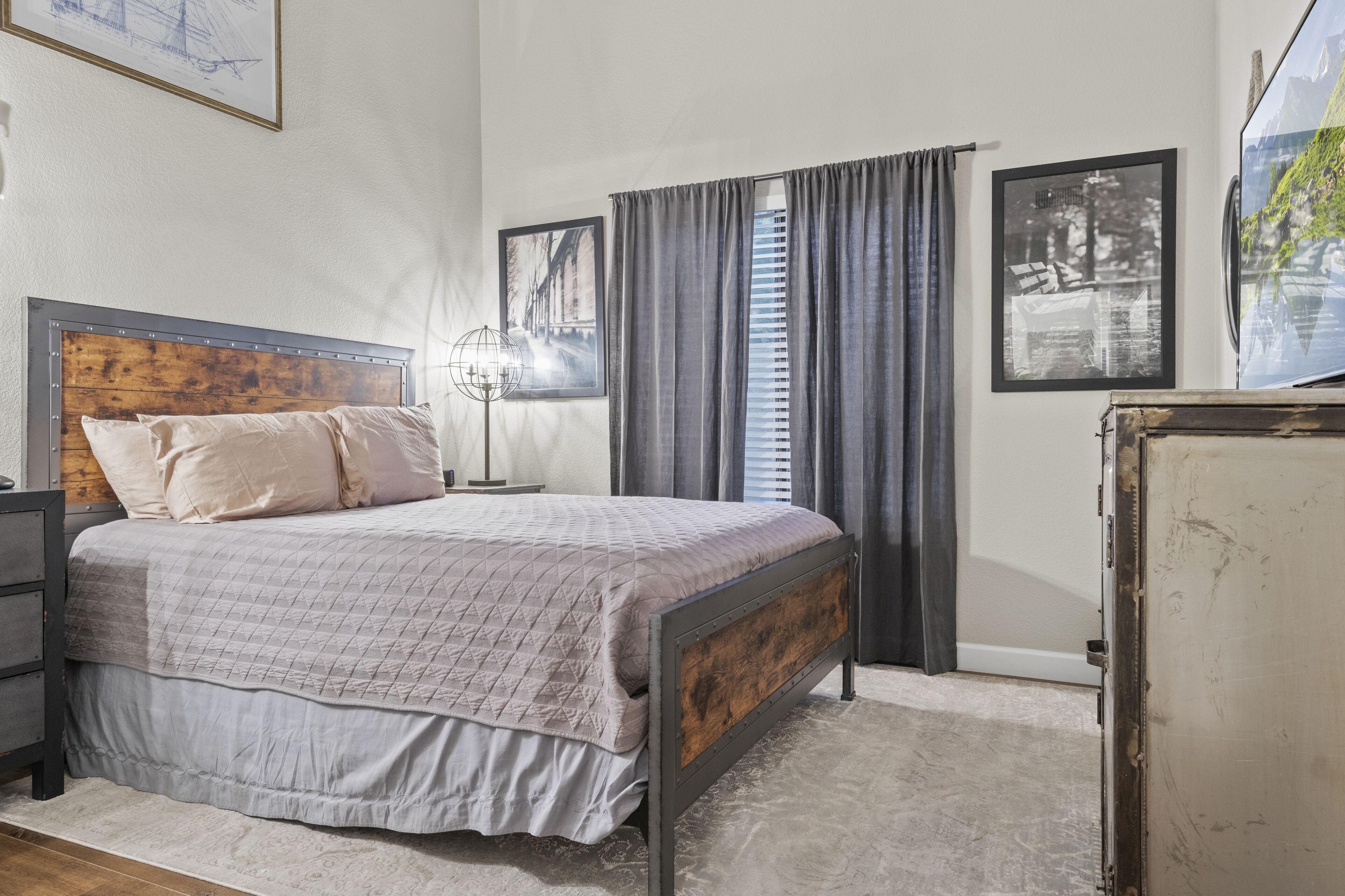 Une chambre à coucher avec un lit doté d’une tête de lit en bois, une table de chevet, une lampe sur pied et une commode.