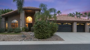 A house with a tiled roof, a garage, and a well-maintained garden with various plants and a small tree. - Stunning North Scottsdale Home w/Heated Pool and Hot Tub (Scottsdale)