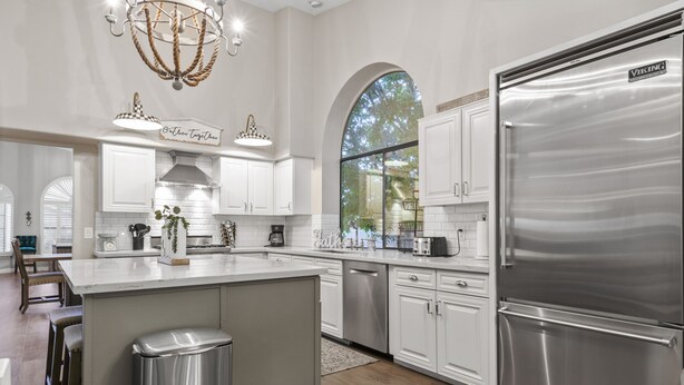 A modern kitchen with white cabinetry, a stainless steel refrigerator, and a large island. - Stunning North Scottsdale Home w/Heated Pool and Hot Tub (Scottsdale)