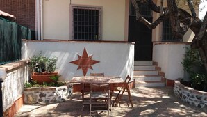 An outdoor patio with a wooden table and chairs, a star decoration on the wall, and potted plants. - Villa dei focesi (Marina di Ascea)