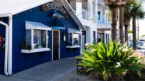 A coastal building with a blue facade, a sign reading "BLUE MARLIN," and a visible grill area. - West Bay Cove 131 · Skyway Views · 30-Night Min (Holmes Beach)