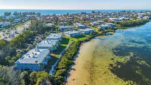 A coastal residential area with beachfront properties, clear skies, and a visible road.
