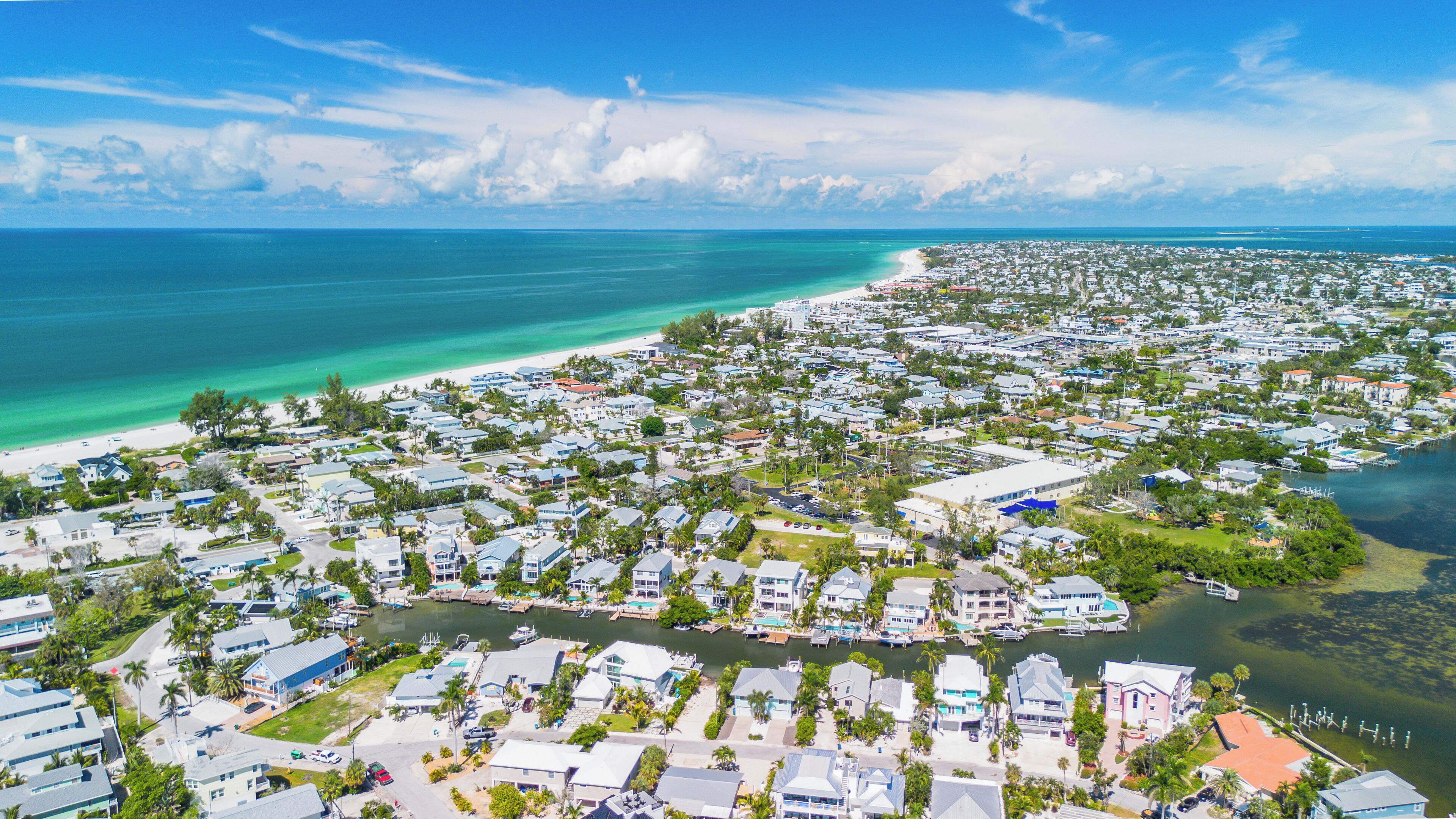 Une zone résidentielle côtière comprenant des maisons, un port de plaisance et une plage.