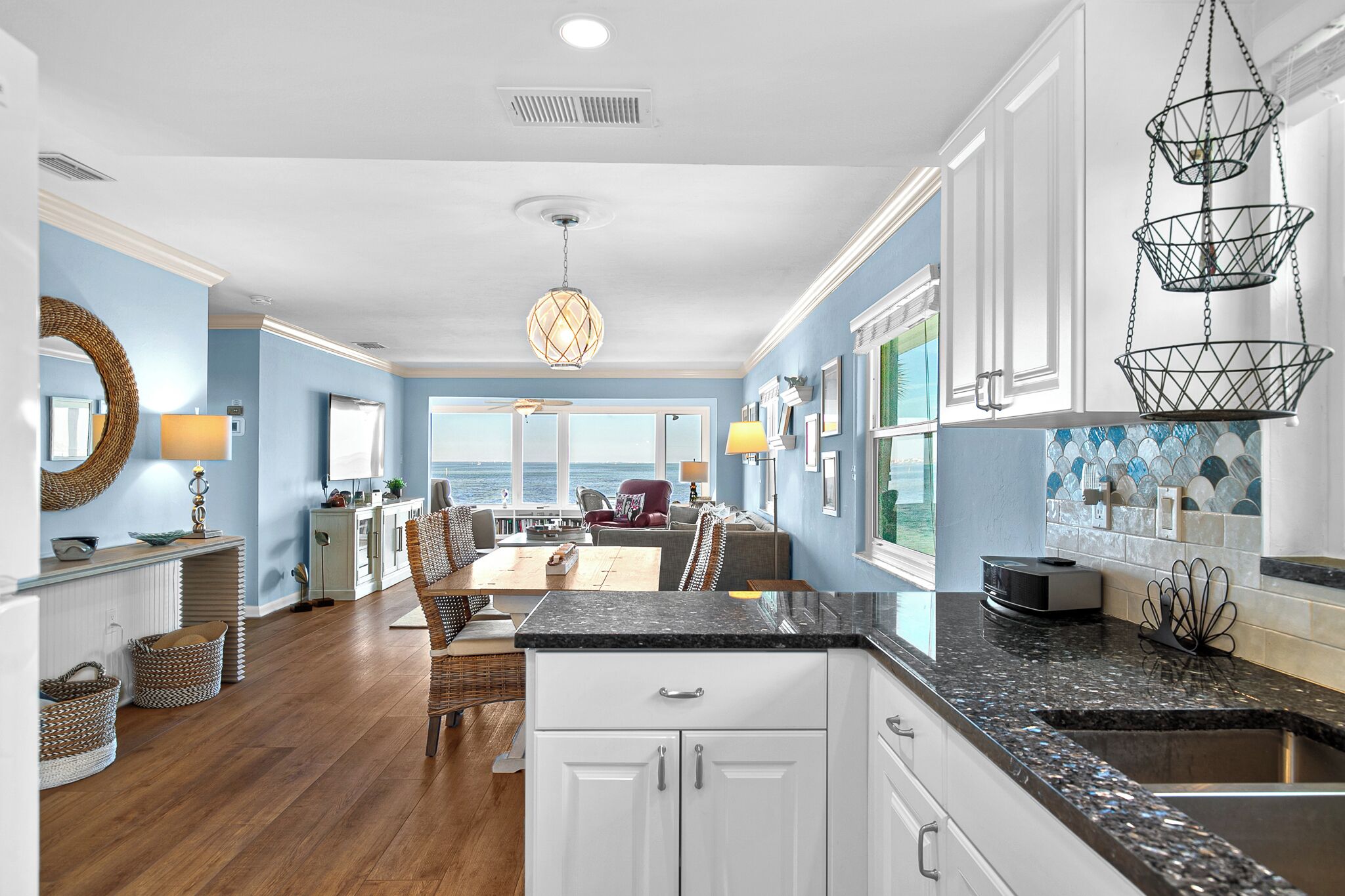 A modern kitchen with granite countertops, white cabinets, and a hanging light fixture.