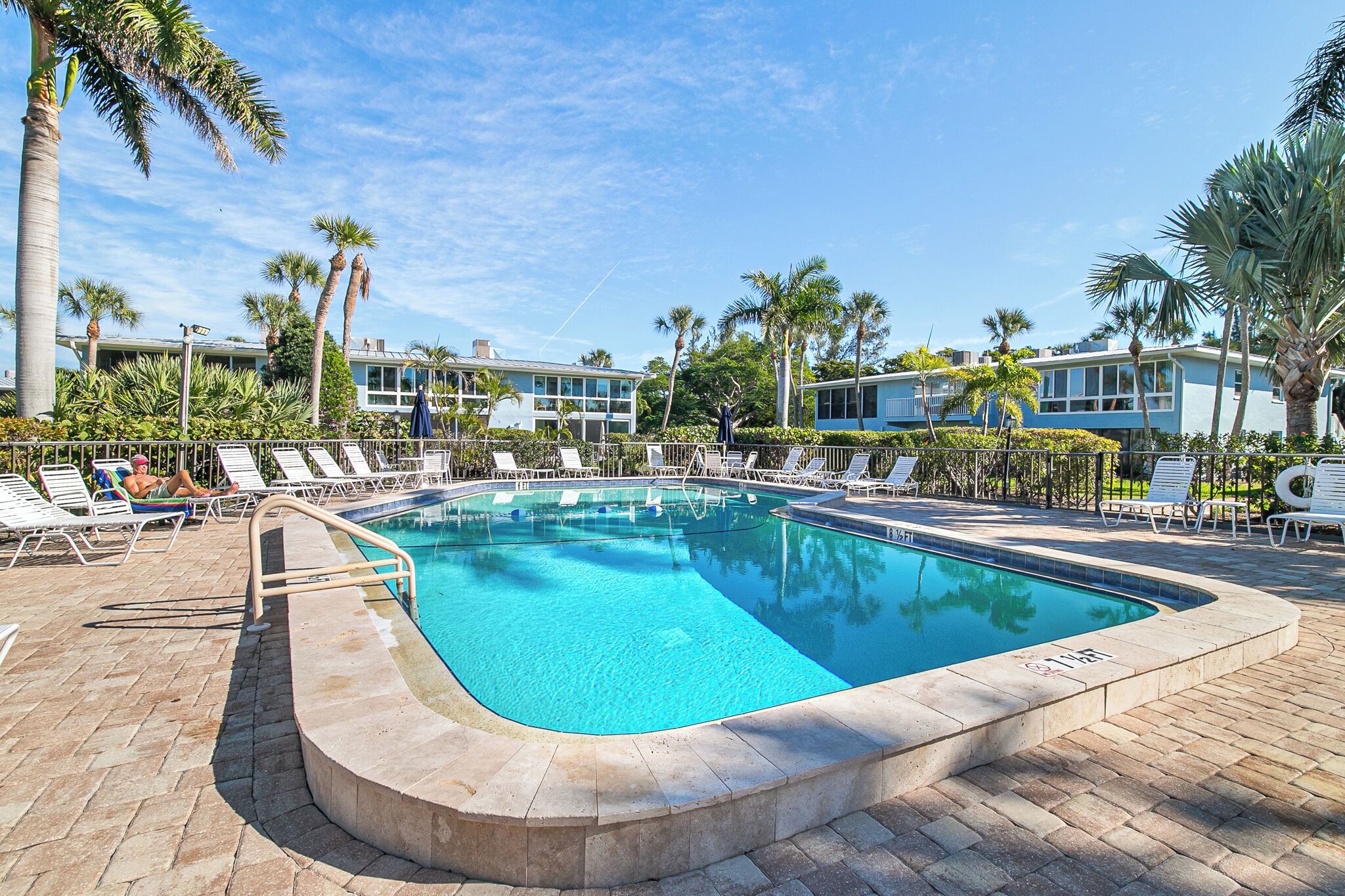 A swimming pool with lounge chairs and palm trees.