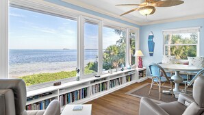 A sunroom with large windows, a ceiling fan, and a view of the ocean. - West Bay Cove 231 · Skyway Views · Sun Room (Holmes Beach)