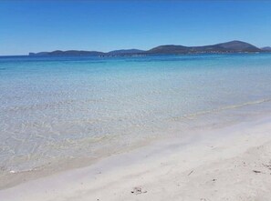 A beach with clear water and distant mountains.