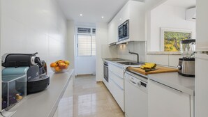 Una cucina moderna con mobili bianchi, forno a microonde integrato e piano di lavoro in legno.