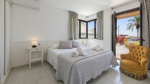A bedroom with a bed, bedside table, chair, and a window with curtains.