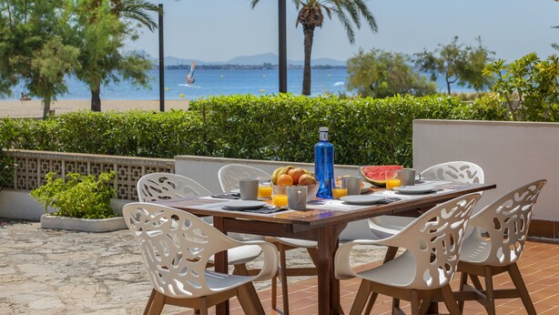 A table set outdoors with chairs, a bottle, and a bowl of fruit.