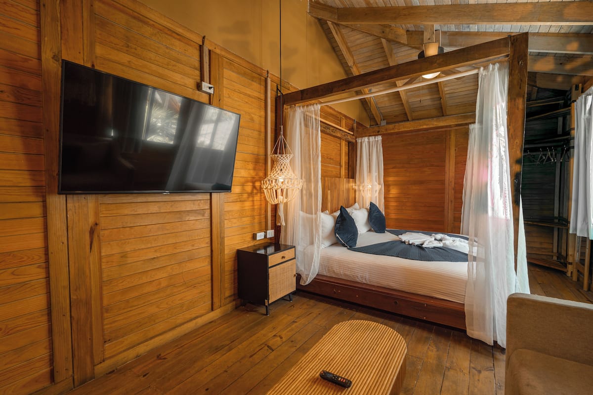 Ein Zimmer in einer Holzhütte mit einem Bett, einem Fernseher und einem Nachttisch.