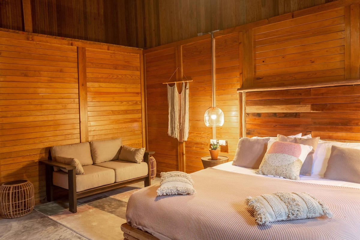 Ein gemütlicher Holzraum mit einem Bett, einer Couch und einer Pendelleuchte.