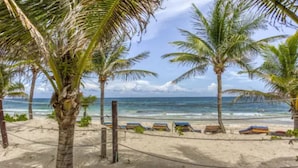 A beach with palm trees, a sandy shore, and a clear view of the ocean. - Nílu Isla Mujeres by Selina (Isla Mujeres)