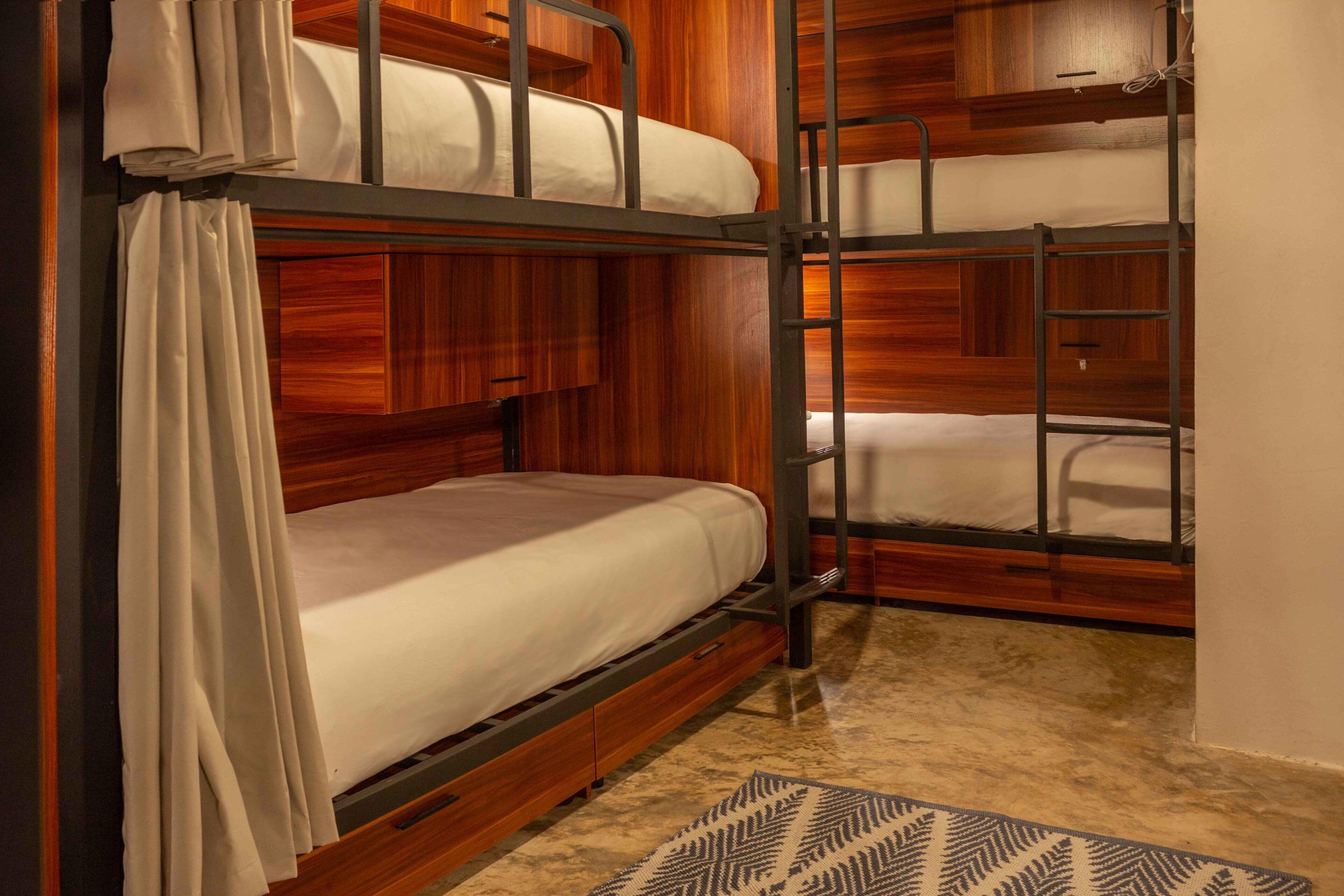 Habitación con literas, paneles de madera, una escalera y una alfombra estampada.