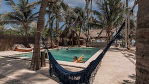A pool area with a hammock, lounge chairs, and palm trees. - Nílu Isla Mujeres by Selina (Isla Mujeres)