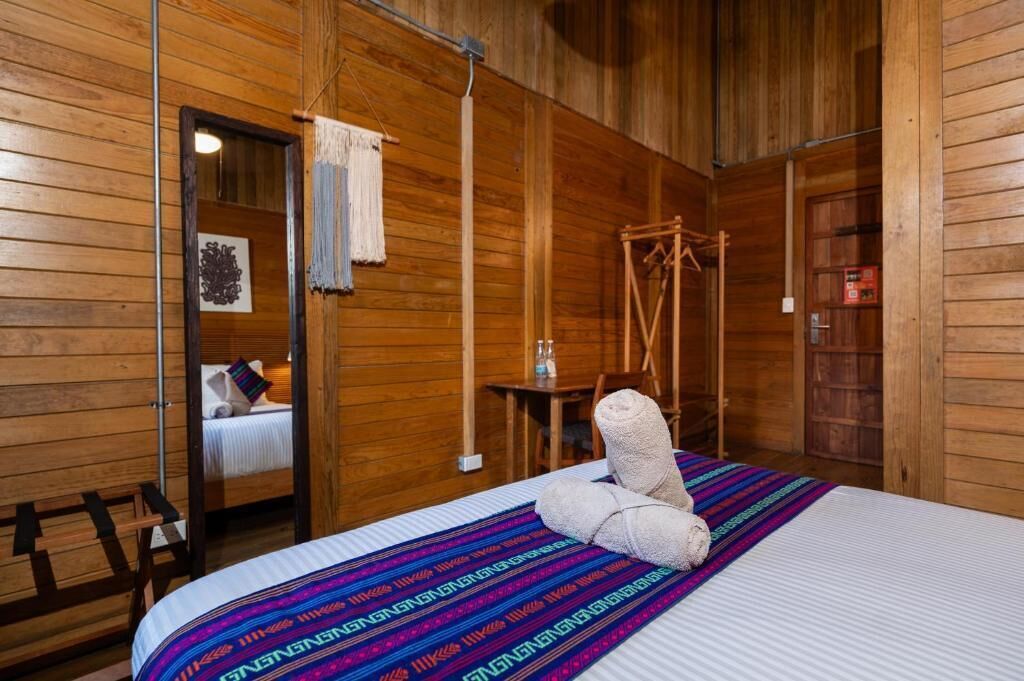 Una habitación de madera con una cama, una mesita y una silla.